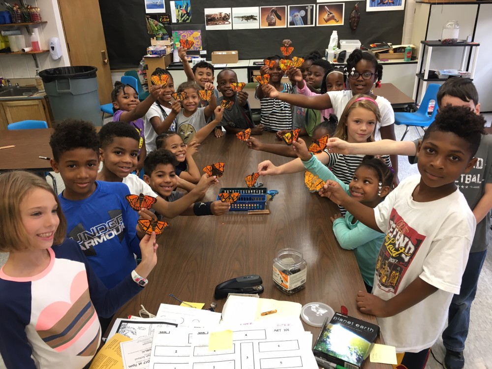 Students hold up their symbolic monarchs in the classroom