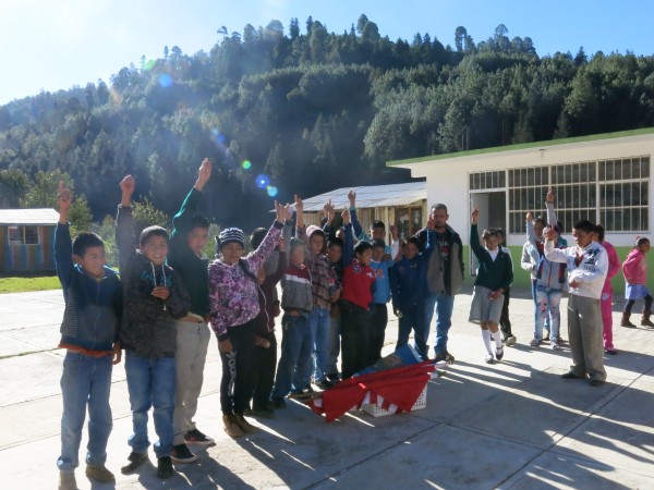 Students greet Estela from the entrance to their classroom.